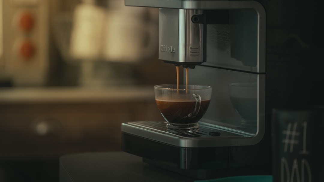 A clean coffee maker with a steaming cup of coffee beside it, showcasing the process of descaling and maintenance.